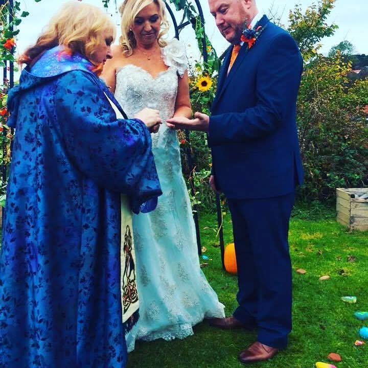 Garden wedding ceremony with Rev. Marie-Louise Jones exchanging rings